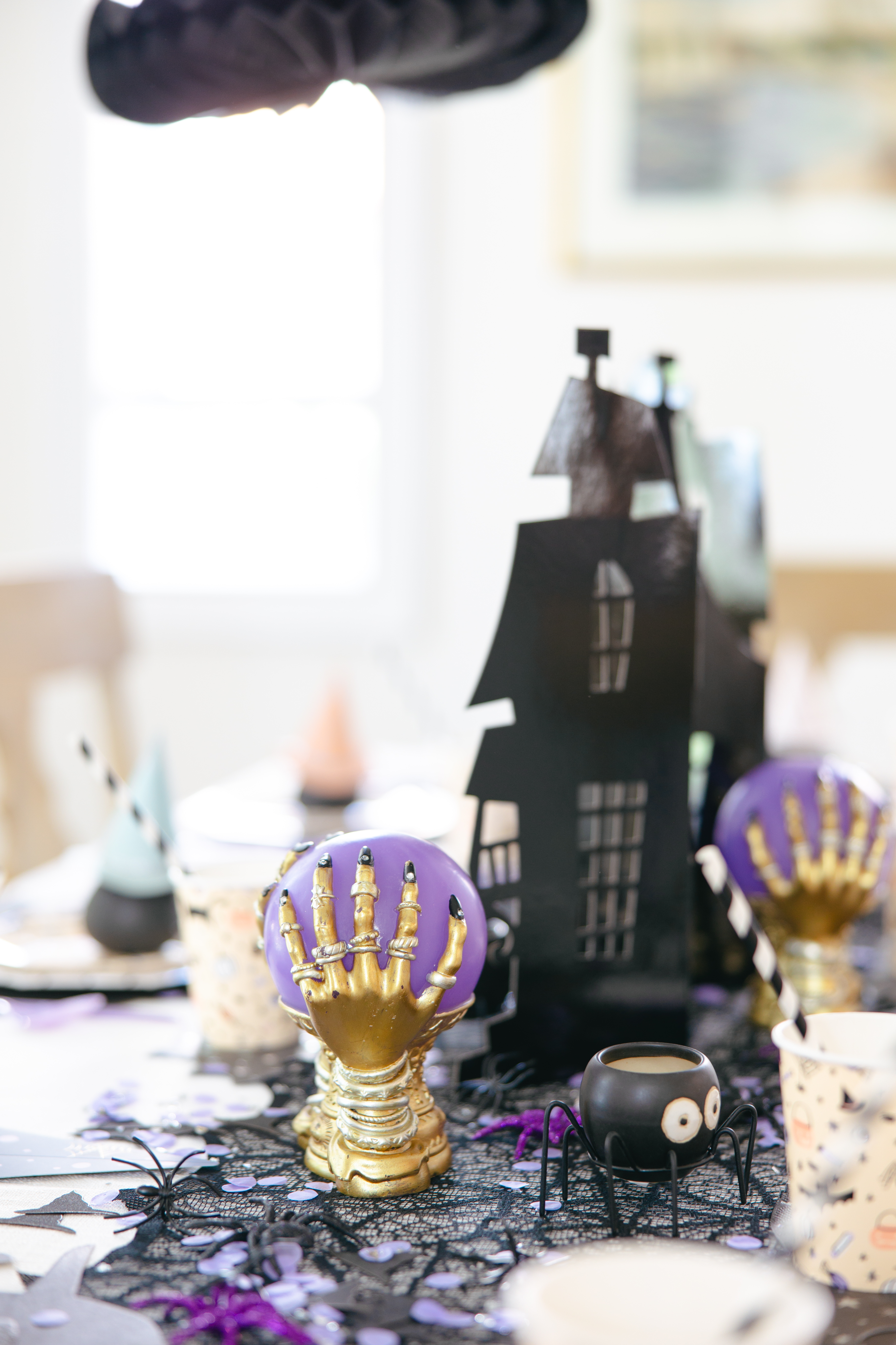 Table centerpiece with cutout black haunted house paper stand and purple and gold crystal balls from Homegoods.
